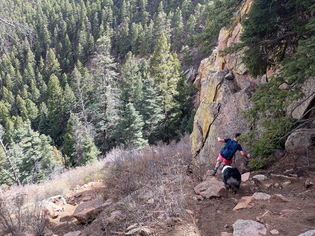 Man and dog scramble down steep mountainside